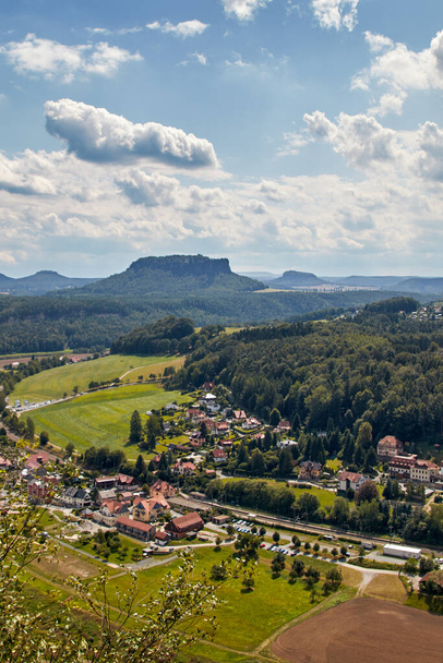Paisaje de la montaña llamada Lilienstein, vista desde el mirador Bastei en la Suiza sajona, una zona de naturaleza y senderismo en Alemania. La pequeña ciudad de Rathen se puede ver en primer plano. - Foto, imagen