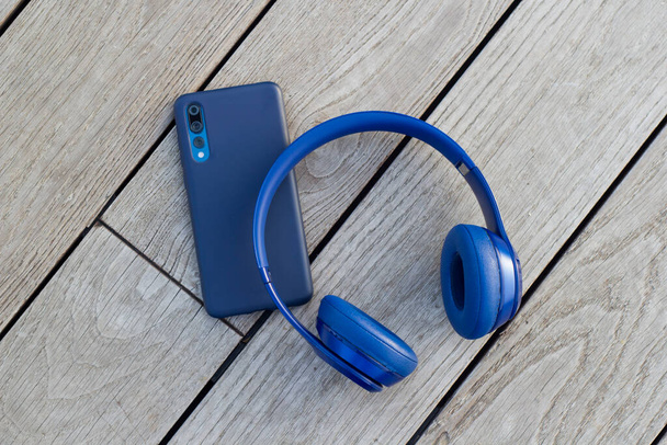 Blue headphones and smartphone on wooden background - Фото, изображение