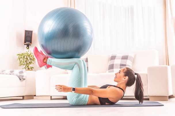 Exercício de abdominais usando uma bola de ajuste realizada por uma atleta atraente em casa
. - Foto, Imagem