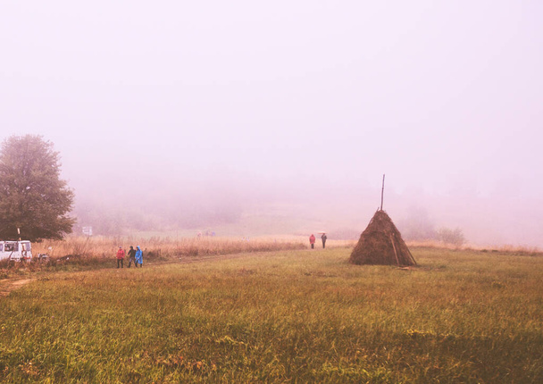 Gente caminando en el paisaje rural, niebla día de otoño, senderismo y exploración de la naturaleza salvaje. Excursionistas irreconocibles, retrovisor. Vida activa saludable
. - Foto, imagen