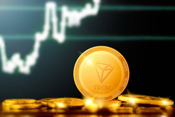 TRON (TRX) Kryptowährung; TRON Goldmünze auf dem Hintergrund des Diagramms - Foto, Bild