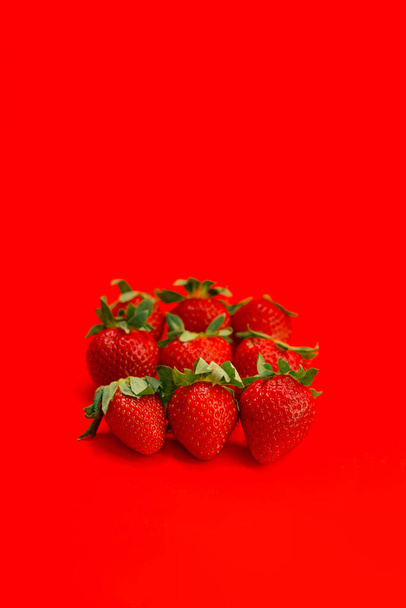 Close-up of fresh strawberries on a red background. Summer berry. Vitamins. The concept of proper nutrition. - Foto, Imagen