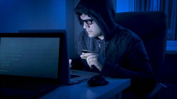 Hombre hacker en la capucha robar dinero de la tarjeta de crédito por la noche
 - Foto, imagen