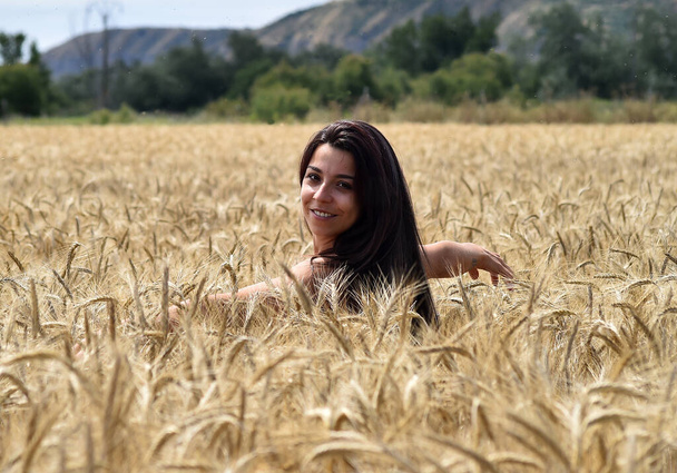 Ένα όμορφο κορίτσι σε ένα χωράφι με χρυσά καρφιά στην ελευθερία - Φωτογραφία, εικόνα