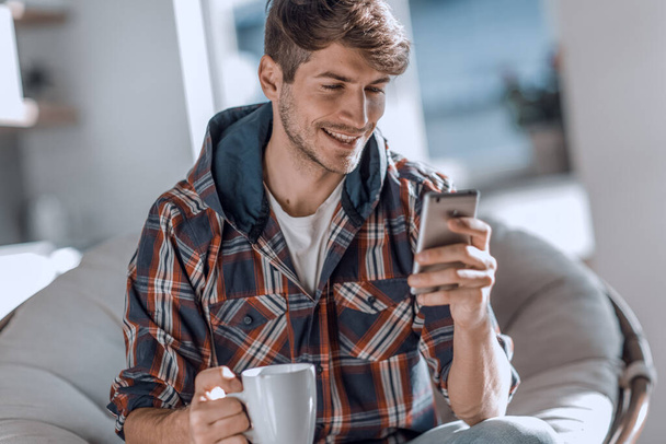 attractive young man drinking coffee and reading SMS. - Φωτογραφία, εικόνα