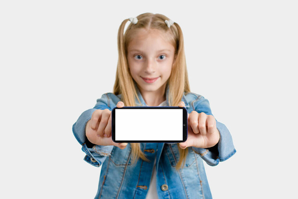 Menina segurando um smartphone em suas mãos com um lugar branco vazio para texto. Concentra-te no telefone. Antecedentes turvos
 - Foto, Imagem