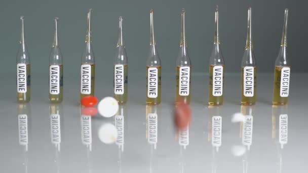 Veel tabletten en pillen vallen in slow motion voor glazen flessen. Verplichte vaccinaties, vaccin tegen coronavirus - Video