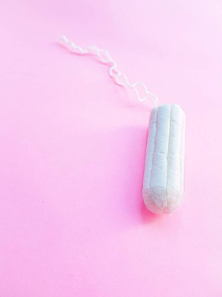 Womens hygiene intimate accessories. A clean white tampon on a pink background. Menstrual cycle. Space for text. - Photo, Image