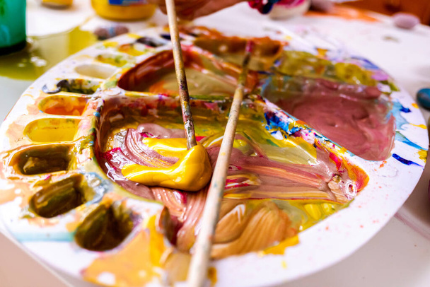 Una chica usa un pincel de pintura acrílica para hacer sus dibujos sobre lienzo
. - Foto, imagen