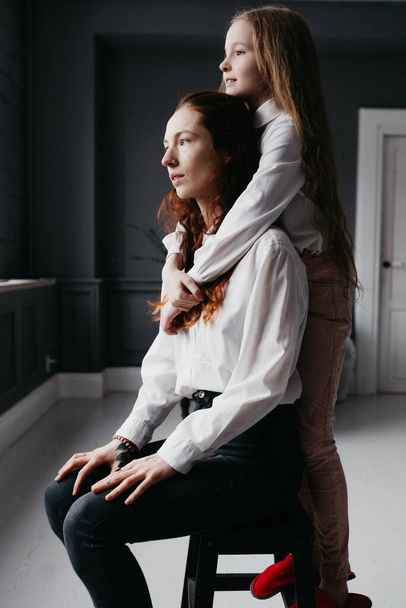 Yong and adult sisters embrace in the loft, representing friendship, trust, similarity - Fotografie, Obrázek