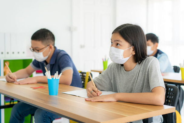 Group of Asian elementary school students wearing hygienic mask to prevent the outbreak of Covid 19 in classroom while back to school reopen their school, New normal for education concept - Zdjęcie, obraz