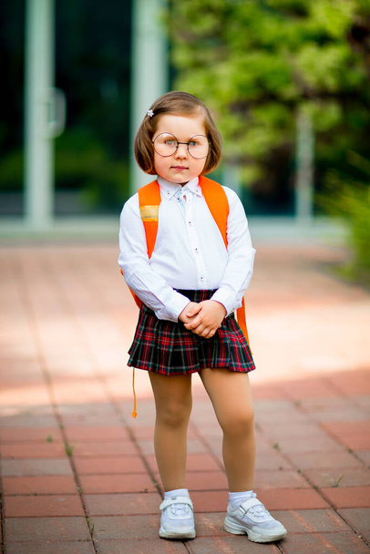Ένα όμορφο κοριτσάκι με γυαλιά και σχολική στολή. - Φωτογραφία, εικόνα
