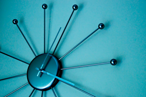 Бирюзовое освещение придает этим стильным современным настенным часам с металлической отделкой драматический вид
 - Фото, изображение