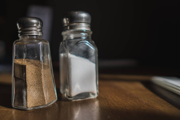 Pojemnik na sól i pieprz na drewnianym stole w kawiarni - Zdjęcie, obraz