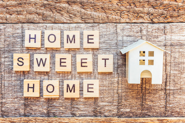 Miniatyyri lelutalo kirjoitus HOME SWEET HOME kirjaimet sana puinen tausta. Asuntolainavakuutus unelma kotiin käsite. Tasainen lay top näkymä, kopioi tilaa - Valokuva, kuva