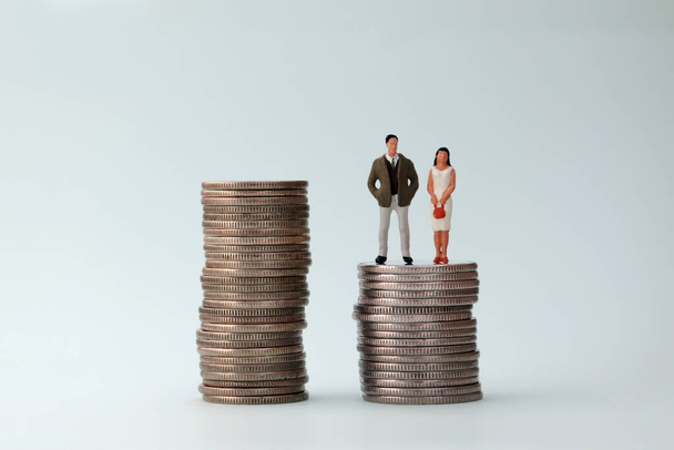 Dos pilas de monedas con una mujer en miniatura y un hombre en miniatura
. - Foto, Imagen