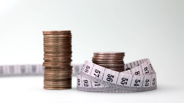 Two pile of coins and tape measure. Cost cutting concept. - Foto, Imagen