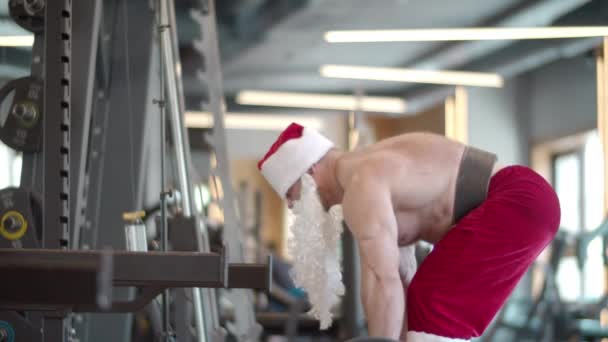Aktivní fitness muž dělá v tělocvičně mrtvou. Muž v kostýmu Santa Cvičení - Záběry, video