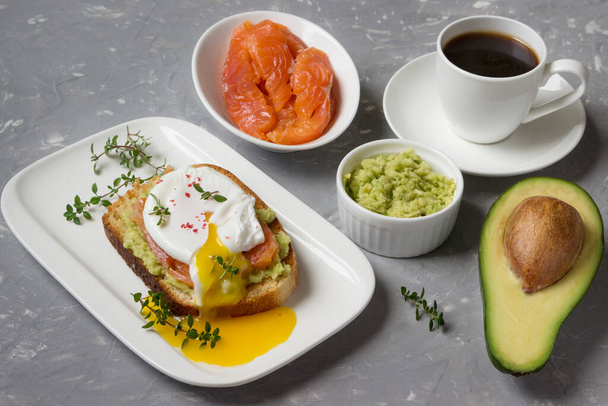 Poached egg with smoked salmon, avocado, toasted bread and coffee  on a white plate. - Photo, image