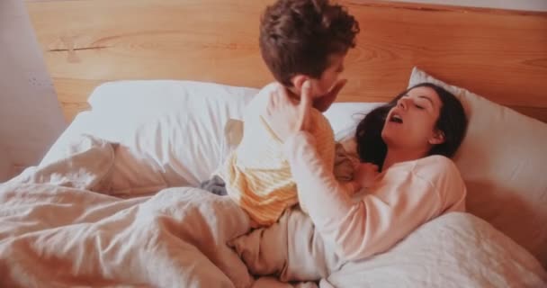 Mother and son having fun in bed in the morning - Filmati, video