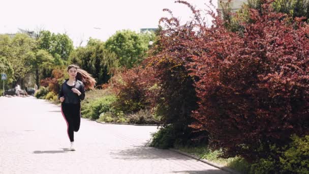 Pretty athletic woman is jogging outdoors - Video