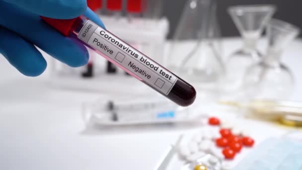 Coronavirus blood test tube. Microbiologist or Doctor hand with blue gloves marking blood test result as positive. Covid-19 positive test virus - Video