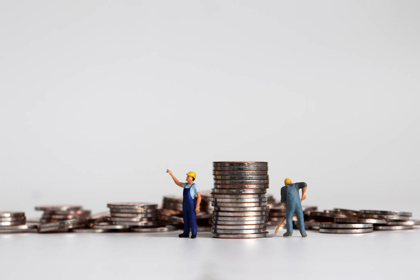 Miniature workers carrying piles of coins. - Photo, Image