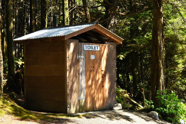 Une image d'une vieille toilette publique extérieure en bois dans un espace boisé
.  - Photo, image