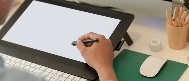 Close up view of male graphic design working on drawing tablet with stylus pen and computer on white desk - Photo, Image