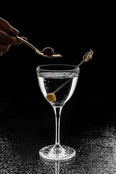 Cocktail alcolico fresco con vodka e olive in bicchiere da vino su fondo nero. Bevanda fredda estiva e cocktail
 - Foto, immagini