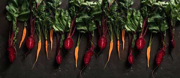 Cékla és sárgarépa sötét háttérrel. Friss zöldségek, egészséges bioélelmiszerek, betakarítás, mezőgazdaság, felülnézet - Fotó, kép