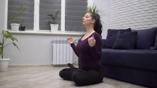 Attractive woman meditating at cozy home, yoga lotus pose, relaxing - Footage, Video