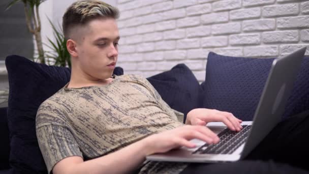 Hombre escribiendo en el teclado, utilizando el ordenador portátil, relajarse en el sofá, freelance, cuarentena
 - Imágenes, Vídeo