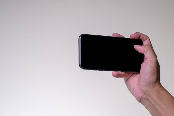 Close up Hand man gospodarstwa smartfon z czarnym ekranem izolowane na żółtym tle - Zdjęcie, obraz