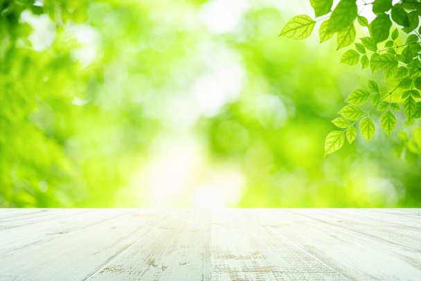Friss zöld levelek természet bokeh az üres fa asztal háttér termék kijelző sablon és másolás tér segítségével a háttér természetes növényzet - Fotó, kép