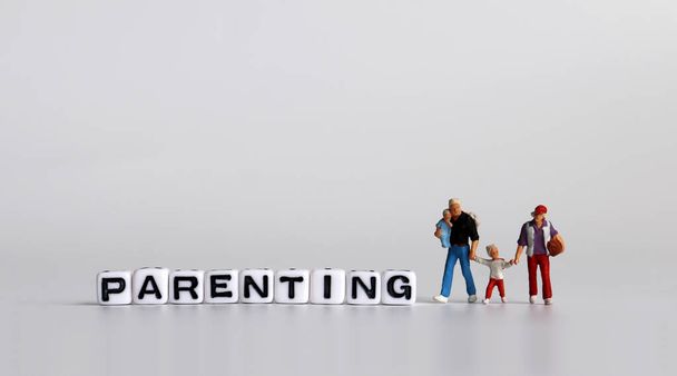 PARENTING text written in white cube. Miniature people with baby. - Photo, Image
