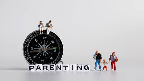 PARENTING text written in white cube. Miniature people and a compass. - Photo, Image