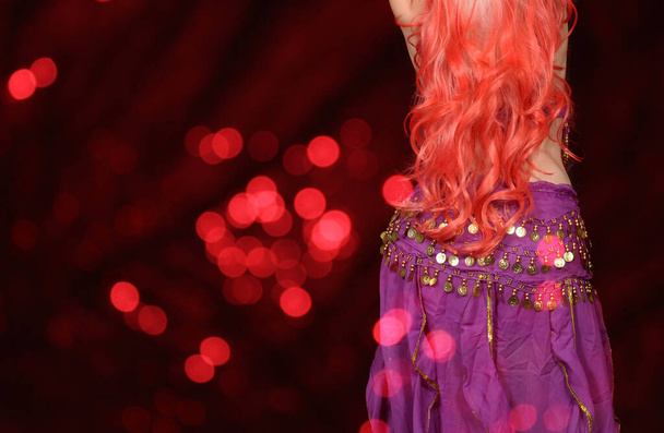 Bailarina del vientre Primer plano vistiendo púrpura con fondo rojo Bokeh
  - Foto, imagen