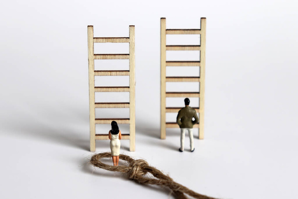 The back of A miniature woman and a miniature man standing in front of a wooden ladder. - Fotó, kép