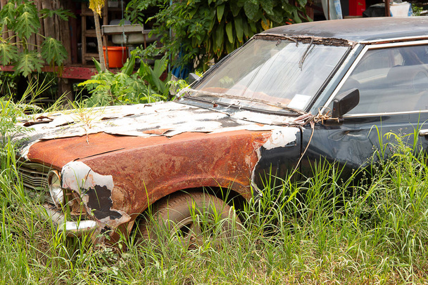 El viejo coche estaba estacionado hasta que se oxidó, se deterioró y la hierba rodeó el coche
. - Foto, Imagen