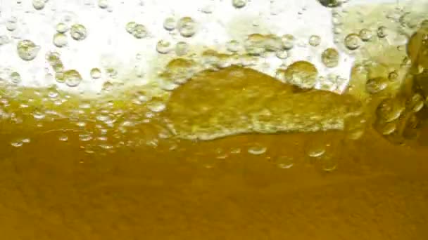 Bolle di liquido dorato. L'olio d'oliva viene mescolato in un cerchio in una ciotola e appaiono bolle d'aria. L'attenzione dell'olio giallo bollente è diffusa, la consistenza della bolla e la macro di molte goccioline diverse.
. - Filmati, video