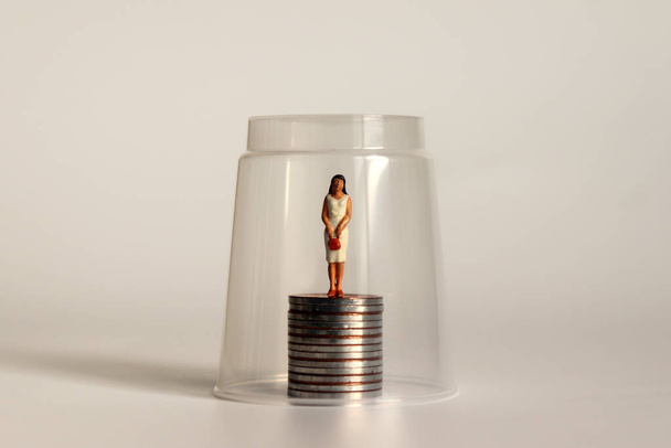Koncept skleněného stropu. Miniaturní ženy a mince. - Fotografie, Obrázek