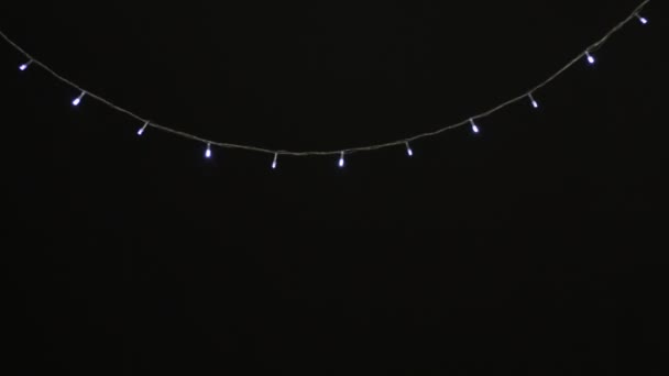 Χριστουγεννιάτικα Φώτα, γιρλάντα με μικρούς λαμπτήρες LED που λάμπουν σε μαύρο φόντο. - Πλάνα, βίντεο