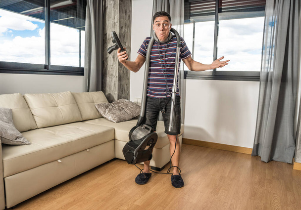 Man desperately trying to understand how a vacuum cleaner works to vacuum the living room. Full body. - Photo, Image