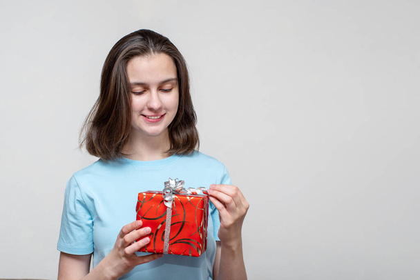 Birthday present, christmas present or new year present concept. Cute young girl holds a red gift box, opens a gift box. - Foto, imagen