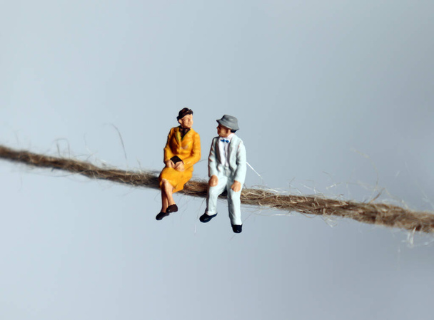 Een miniatuur bejaardenpaar dat aan een touw zit. Concepten over de tekortschietende maatregelen van een vergrijzende samenleving. - Foto, afbeelding