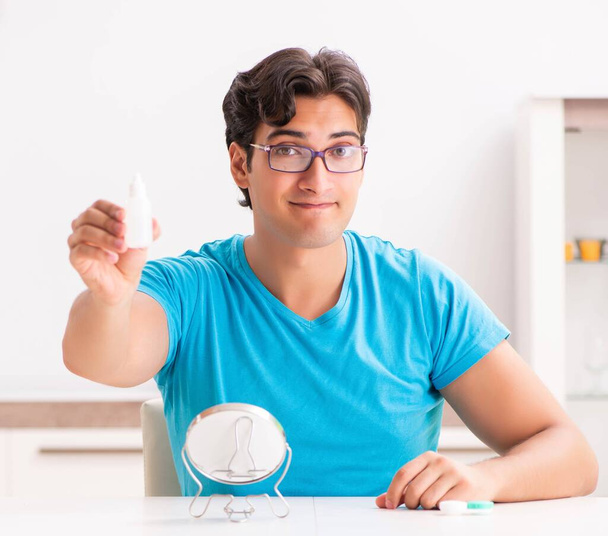 Hombre tratando de lentes de contacto en casa
 - Foto, Imagen