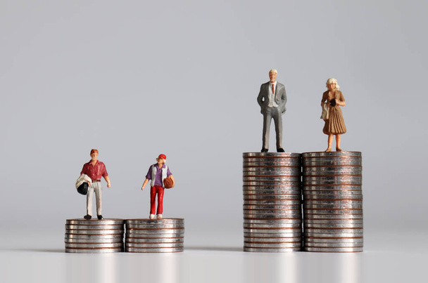 Miniature people with pile of coins. The concept of social stratification according to economic power. - Photo, Image