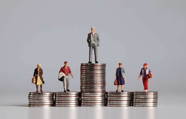 Personas en miniatura con pila de monedas. Un concepto de desigualdad de ingresos
. - Foto, imagen