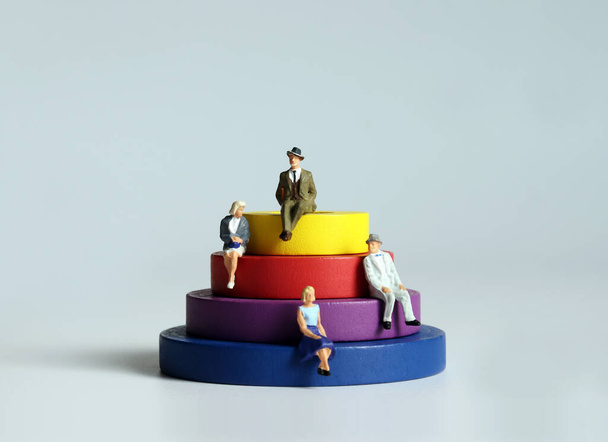 Round wooden blocks and miniature people. The concept of social stratification. - 写真・画像